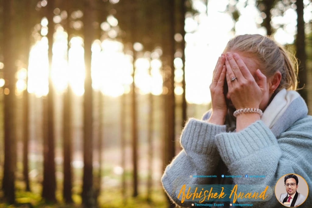 woman wearing gray coat with hands on her face during daytime