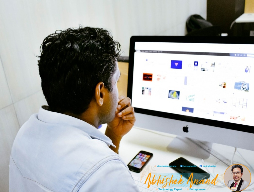 man sitting in front of silver Apple iMac on table